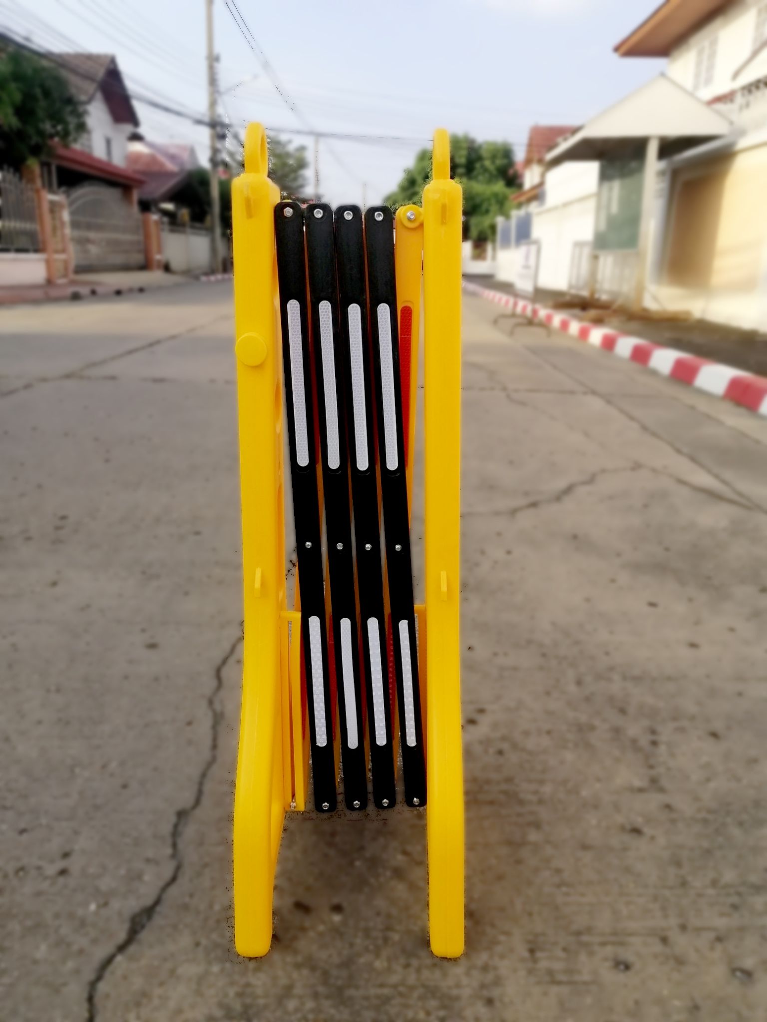 แผงกั้นพลาสติกยืดหดได้สีเหลืองสลับดำพร้อมแถบสะท้อนแสง มุมมองด้านหน้าสำหรับกั้นพื้นที่จัดวางบนพื้นเรียบ