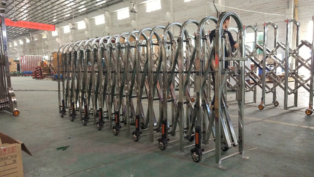 ประตูโฟลดิ้งเกท Folding Gate สีเงินสแตนเลสแบบพับได้ ติดตั้งบนพื้นเรียบ มุมมองด้านข้างแสดงโครงสร้างเหล็กซิกแซกแข็งแรง