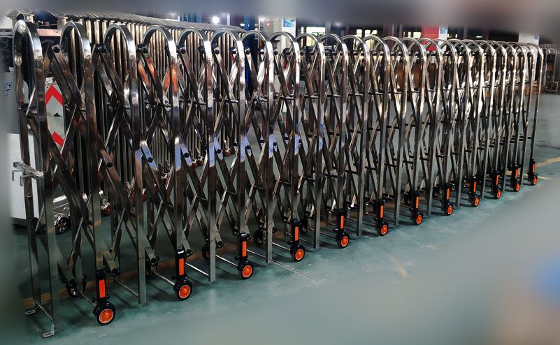 ประตูโฟลดิ้งเกท Folding Gate สีเงินสแตนเลสแบบพับได้ ติดตั้งบนพื้นเรียบ มุมมองด้านข้างแสดงโครงสร้างเหล็กซิกแซกแข็งแรง