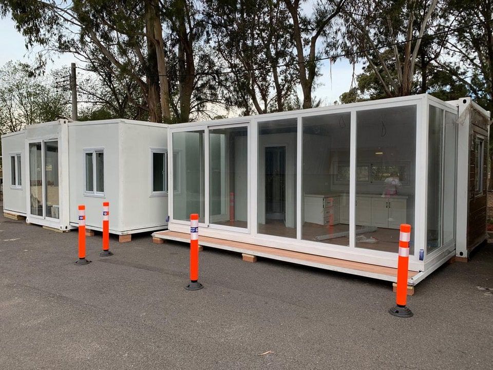 ออฟฟิศสำเร็จรูป TEH-CH08 สำนักงานผนังกระจกขนาด 6x3 เมตร สีขาวดีไซน์ทันสมัย ตั้งอยู่ริมสระว่ายน้ำในบรรยากาศสวนกลางแจ้ง มุมมองเฉียงด้านข้าง