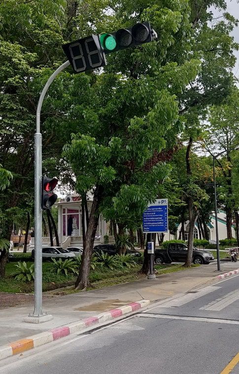 เสาไฟฟ้า Mast arm โค้ง สีเทาเข้ม ดีไซน์แขนยื่นแนวนอน ติดตั้งบนฐานรองรับเหล็กแข็งแรงสำหรับงานระบบไฟฟ้าและแสงสว่าง