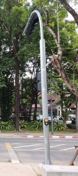 เสาไฟฟ้า Mast arm โค้ง สีเทาเข้ม ดีไซน์แขนยื่นแนวนอน ติดตั้งบนฐานรองรับเหล็กแข็งแรงสำหรับงานระบบไฟฟ้าและแสงสว่าง