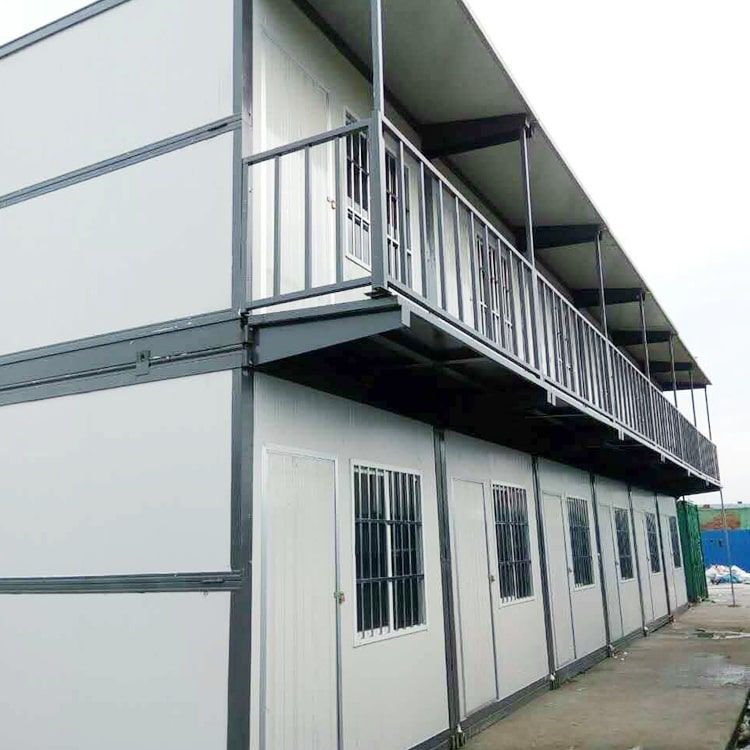 Container House แบบพับได้ (TEH-CH12) สีขาว ดีไซน์ทันสมัย ตั้งอยู่บนสนามหญ้า มุมมองเฉียงเห็นหน้าต่างเหล็กดัดและโครงสร้างตู้พับได้
