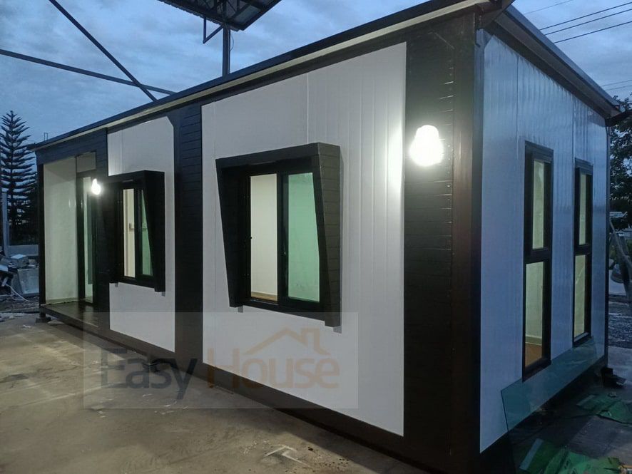 บ้านและออฟฟิศสำเร็จรูปสีขาวตัดขอบไม้ ดีไซน์ทันสมัย มุมมองด้านข้างแสดงประตูและหน้าต่างกระจกบานใหญ่สำหรับใช้งานในสำนักงาน