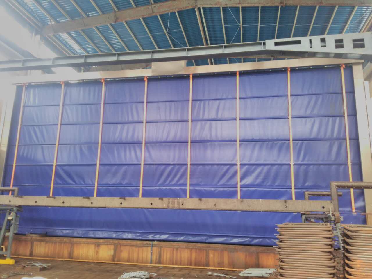 ประตู High Speed door สีน้ำเงินแบบ Stack PVC รุ่น HPD-42 ติดตั้งบนผนังคลังสินค้าขนาดใหญ่ มุมมองตรงหน้าตรง