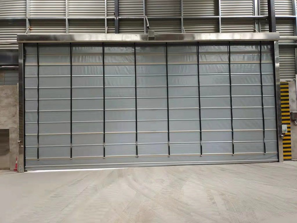ประตู High Speed door รุ่น HPD-49 สีน้ำเงินแบบ Stack PVC ติดตั้งบนผนังโรงงาน มุมมองตรงเห็นแผ่นพลาสติกใสช่วยมองผ่านได้