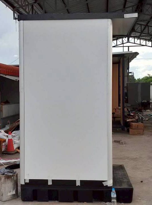 ห้องน้ำสำเร็จรูปสีขาวพร้อมประตูสีเทาและฐานไฟเบอร์สีดำแบบเคลื่อนย้ายได้ มุมมองเฉียงแสดงโครงสร้าง Mobile Toilet สำหรับใช้งานนอกสถานที่